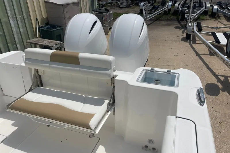Slide: The Image of 2023 Edgewater 262CC boat with dual engines and cushioned seating in a marina setting. - 23