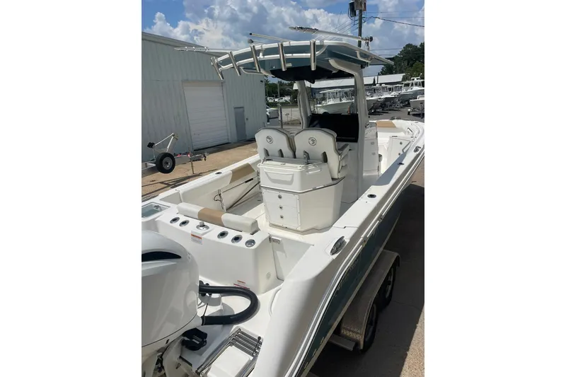 Slide: The Image of 2023 Edgewater 262CC boat with dual console, docked outdoors under a partly cloudy sky. - 6