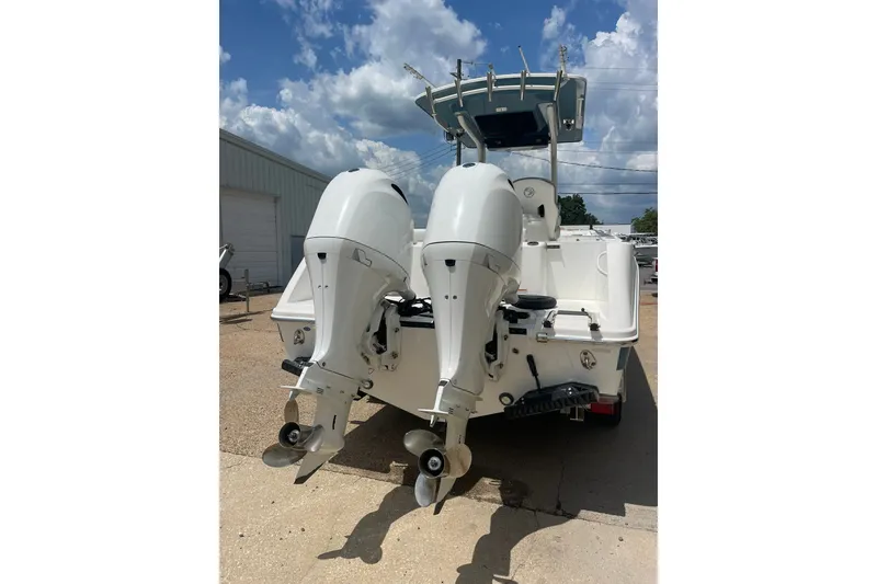 Slide: The Image of 2023 Edgewater 262CC boat with dual outboard motors, parked outdoors under a cloudy sky. - 5