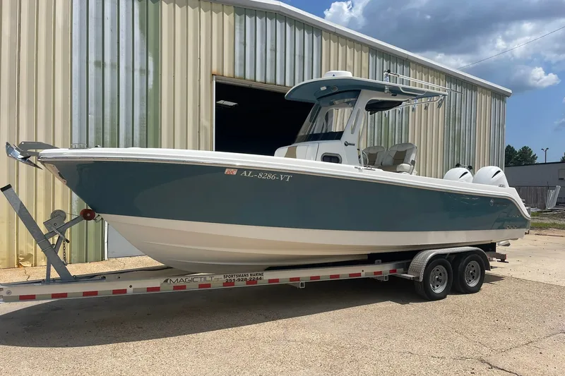 The Image of 2023 Edgewater 262CC boat on trailer outside a metal building under a blue sky. - 0