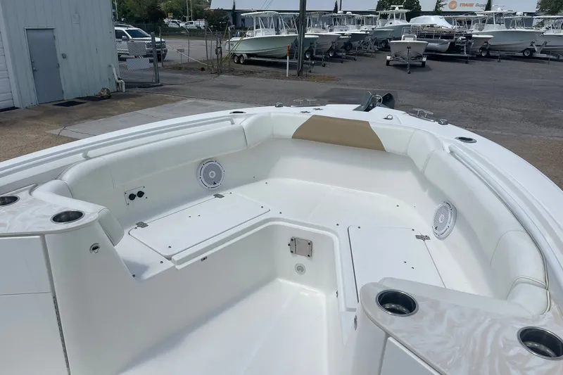 Slide: The Image of 2023 Edgewater 262CC boat interior with seating and cup holders at a marina. - 13