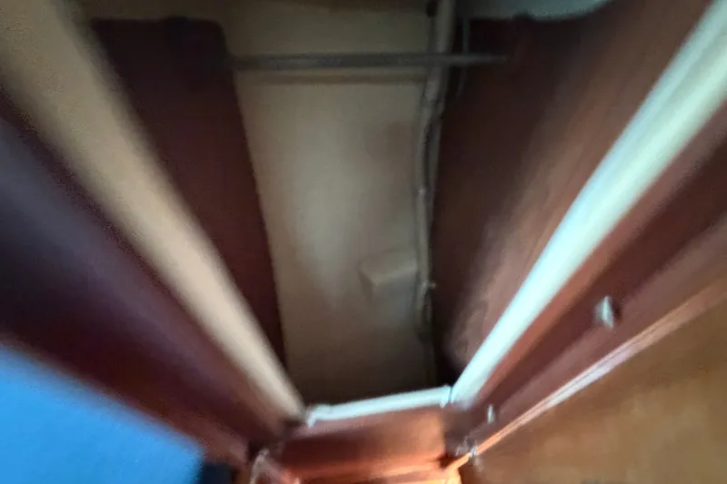 Slide: The Image of Blurred interior view of a 1984 C&C 33 MK II sailboat, showing wooden paneling and storage space. - 56