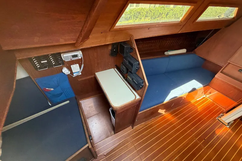 Slide: The Image of 1984 C&C 33 MK II yacht interior with wooden finish and blue seating. - 33