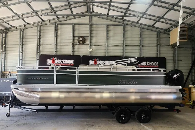 The Image of 2027 Sun Tracker Fishin' Barge 22 DLX pontoon boat in a metal garage. - 1
