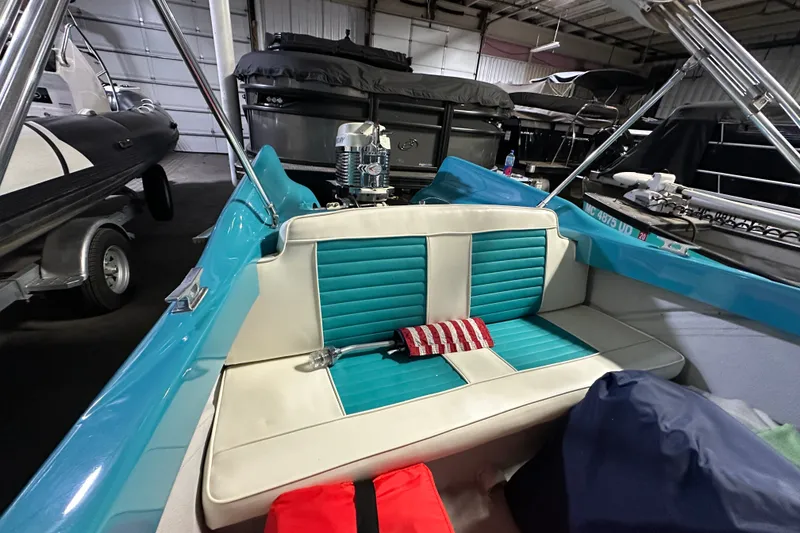 Slide: The Image of 1959 Seafury 14' Antique boat interior with teal and white seating in a storage facility. - 9