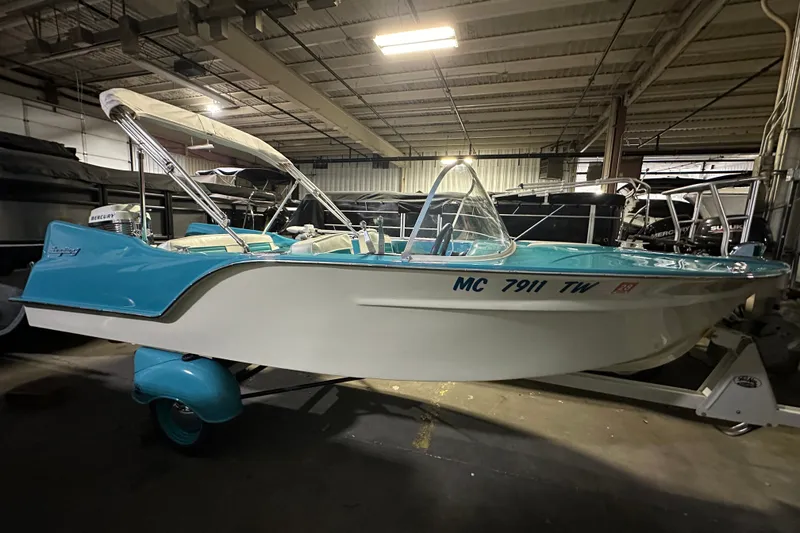 The Image of 1959 Seafury 14' Antique boat with blue and white design in a storage facility. - 0