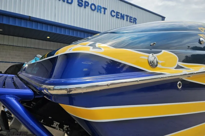 Slide: The Image of 2010 Nor-Tech 4300V boat with vibrant blue and yellow design at a sports center. - 37