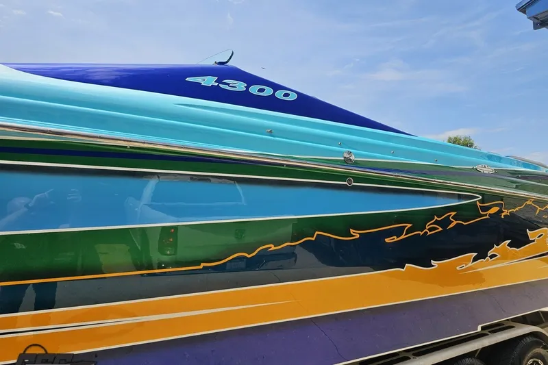 Slide: The Image of Colorful 2010 Nor-Tech 4300V boat with vibrant stripes and sleek design under a clear sky. - 27