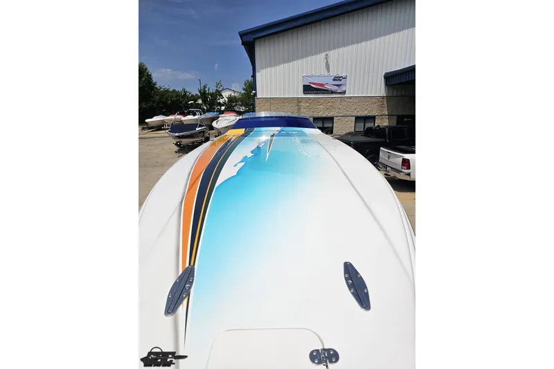 Slide: The Image of 2010 Nor-Tech 4300V boat with vibrant blue and orange design, parked outdoors. - 20