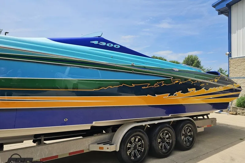 Slide: The Image of 2010 Nor-Tech 4300V speedboat with vibrant blue and yellow design on a trailer. - 25
