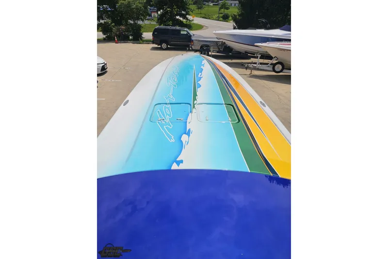 Slide: The Image of Colorful 2010 Nor-Tech 4300V boat with vibrant graphics on deck, parked outdoors. - 76