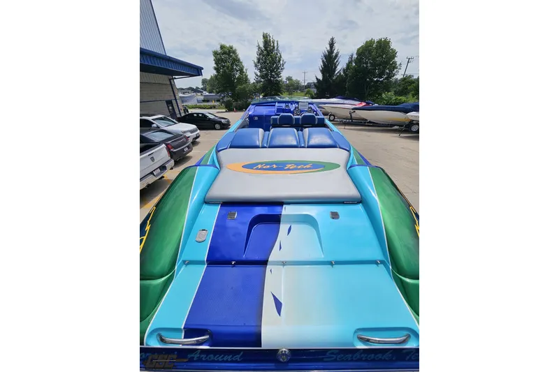 Slide: The Image of 2010 Nor-Tech 4300V powerboat with vibrant blue and green design, parked outdoors. - 50