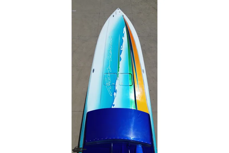 Slide: The Image of 2010 Nor-Tech 4300V boat with vibrant blue, green, and yellow design on deck. - 43