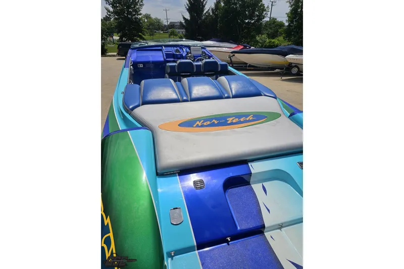 Slide: The Image of 2010 Nor-Tech 4300V powerboat with vibrant blue and green design, docked outdoors. - 49