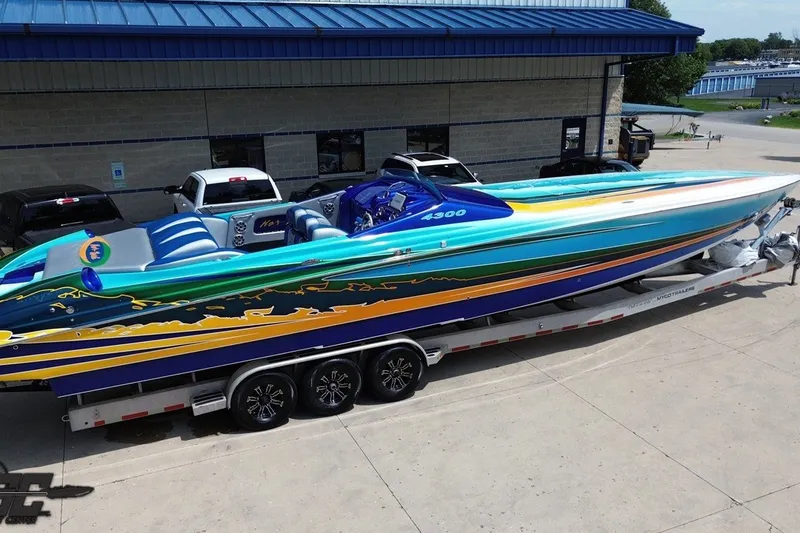 Slide: The Image of 2010 Nor-Tech 4300V powerboat with vibrant, colorful design on a trailer outside a building. - 38