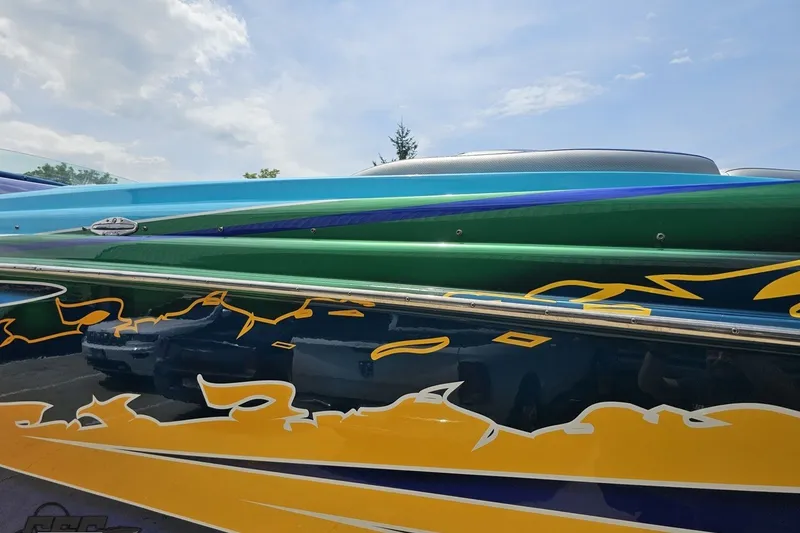 Slide: The Image of Colorful 2010 Nor-Tech 4300V boat with vibrant, artistic side graphics under a clear sky. - 30