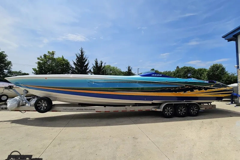 Slide: The Image of 2010 Nor-Tech 4300V powerboat on trailer, vibrant blue and yellow design, sunny day. - 24