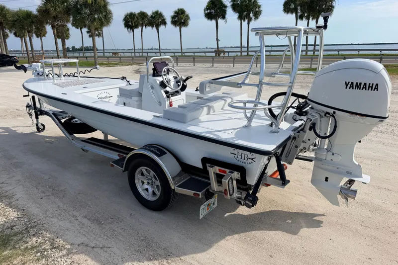 Slide: The Image of 2021 Hell's Bay Marathon boat with Yamaha engine on trailer, parked near palm trees. - 3