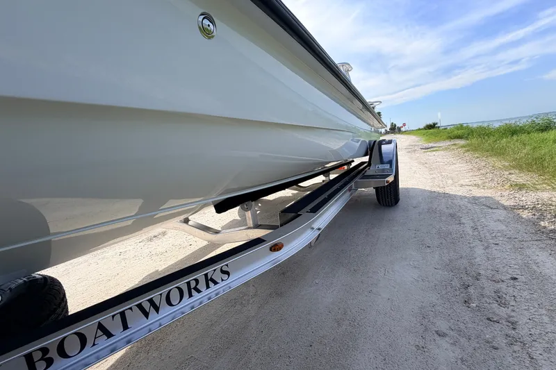 Slide: The Image of 2021 Hell's Bay Marathon boat on trailer, parked on a sandy path by the water. - 15