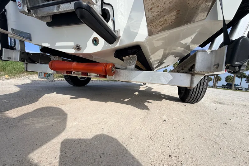 Slide: The Image of 2021 Hell's Bay Marathon boat trailer with orange roller on sandy ground. - 28