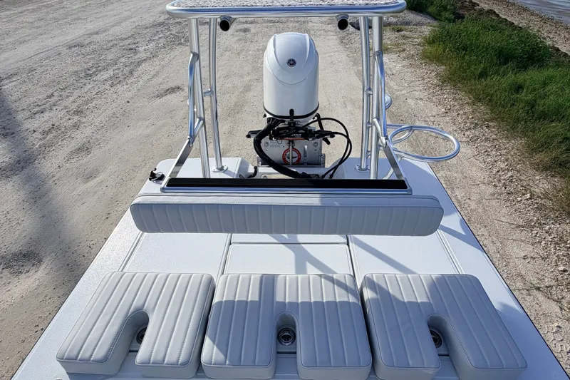 Slide: The Image of 2021 Hell's Bay Marathon boat with cushioned seating and motor, parked on a gravel path. - 66