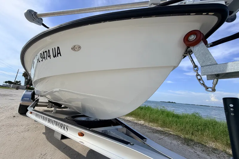 Slide: The Image of 2021 Hell's Bay Marathon boat on trailer by waterfront, showcasing sleek hull design. - 7