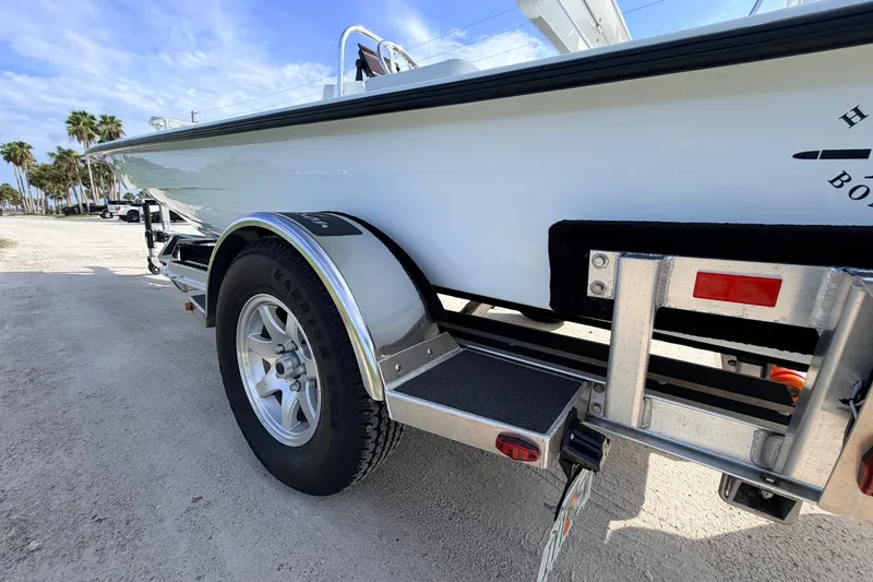 Slide: The Image of 2021 Hell's Bay Marathon boat on trailer, parked on sandy ground with palm trees in background. - 19