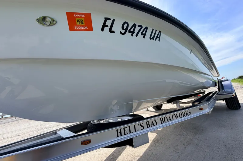 Slide: The Image of 2021 Hell's Bay Marathon boat on trailer, Florida registration visible, under clear blue sky. - 12