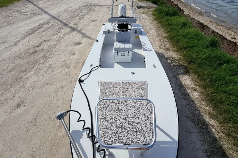 Slide: The Image of 2021 Hell's Bay Marathon boat on sandy shore near water and grass. - 38