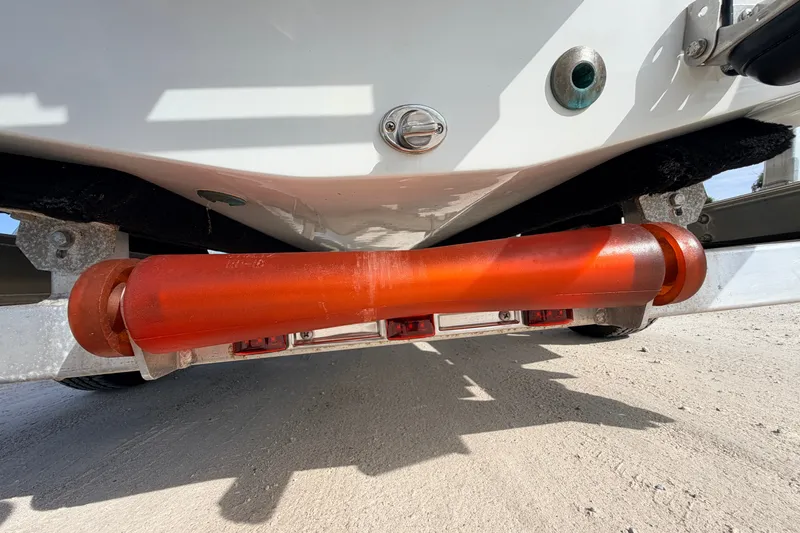Slide: The Image of 2021 Hell's Bay Marathon boat trailer with orange roller on sandy ground. - 23