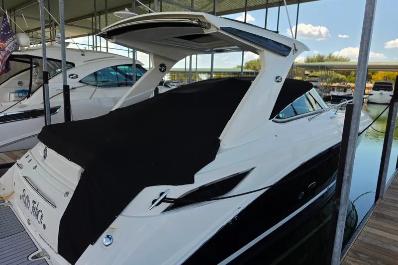 Slide: The Image of 2021 Sea Ray Sundancer 350 docked under a covered marina, featuring sleek design and black cover. - 54