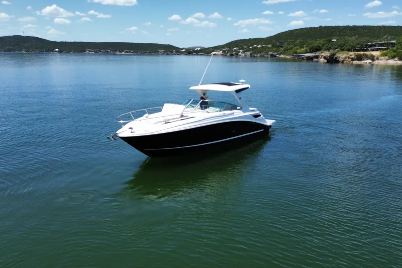 Slide: The Image of 2021 Sea Ray Sundancer 350 yacht cruising on a serene lake under a clear blue sky. - 62