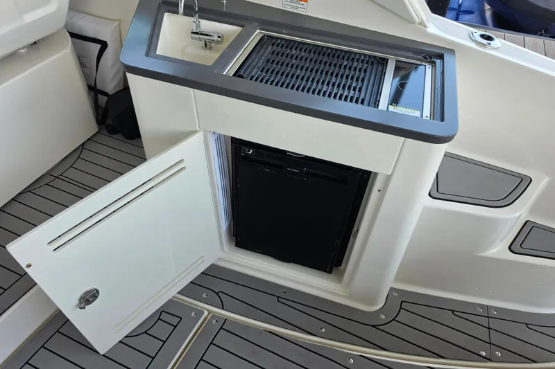 Slide: The Image of 2021 Sea Ray Sundancer 350 boat kitchenette with sink, grill, and open storage compartment. - 23