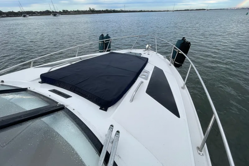 Slide: The Image of 2017 Regal 35 Sport Coupe yacht bow on calm water, featuring sleek design and sun pad. - 15