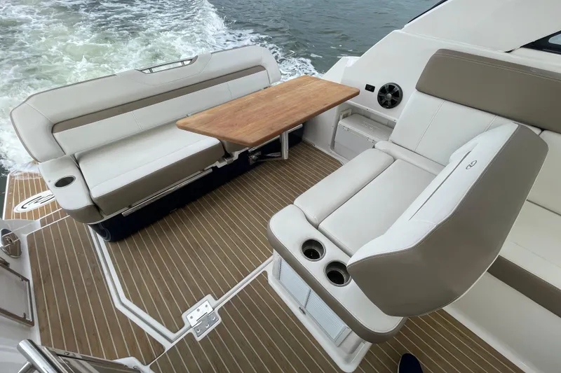 Slide: The Image of 2017 Regal 35 Sport Coupe interior with beige seating and wooden table on deck. - 19
