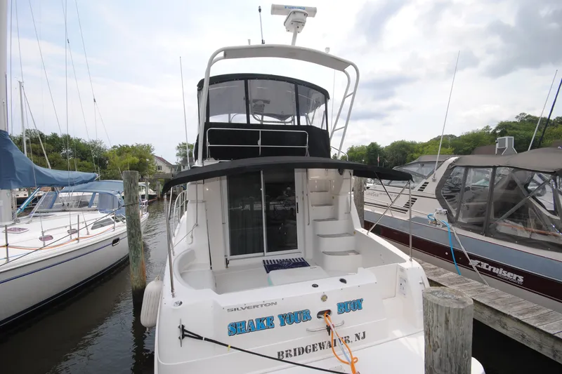 Slide: The Image of 2000 Silverton 351 Sedan yacht docked at marina, featuring upper deck and spiral staircase. - 2