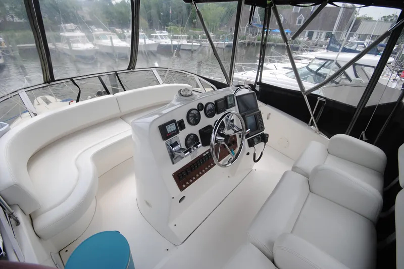 Slide: The Image of Interior view of a 2000 Silverton 351 Sedan yacht cockpit with white seating and control panel. - 11