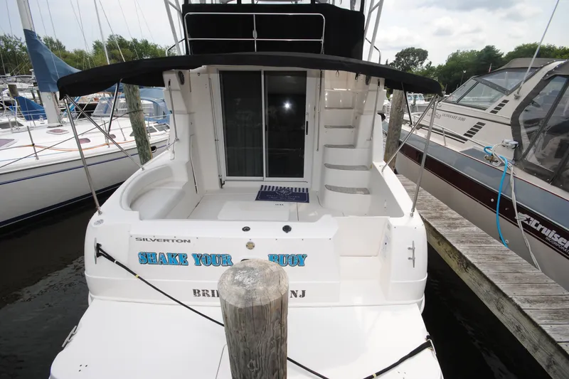 Slide: The Image of 2000 Silverton 351 Sedan yacht docked, featuring spacious deck and sleek design. - 3