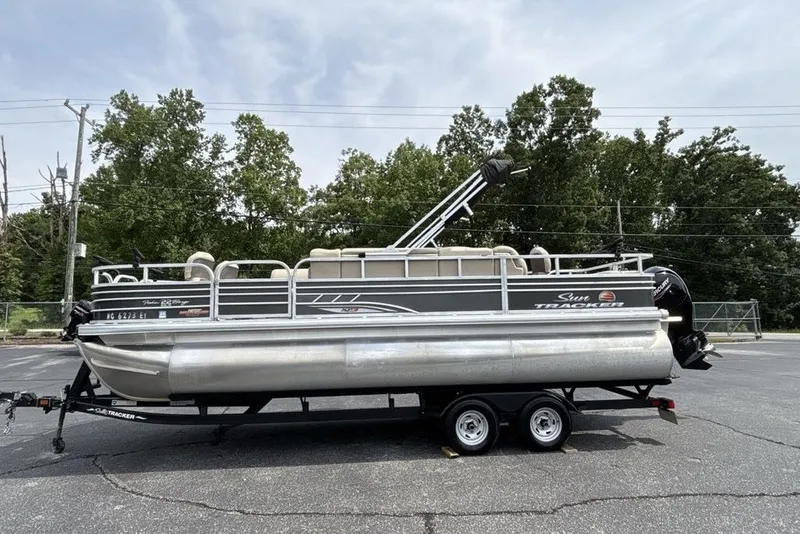 Slide: The Image of 2027 Sun Tracker Fishin' Barge 22 XP3 pontoon boat on trailer, parked outdoors. - 20
