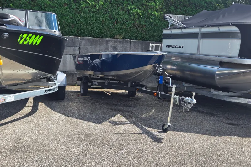 Slide: The Image of A blue Princecraft Yukon 14 L WT boat on a trailer, surrounded by other boats. - 6