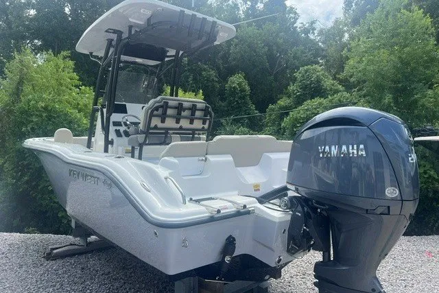 Slide: The Image of 2026 Key West 219 FS boat with Yamaha engine, parked on gravel, surrounded by trees. - 3