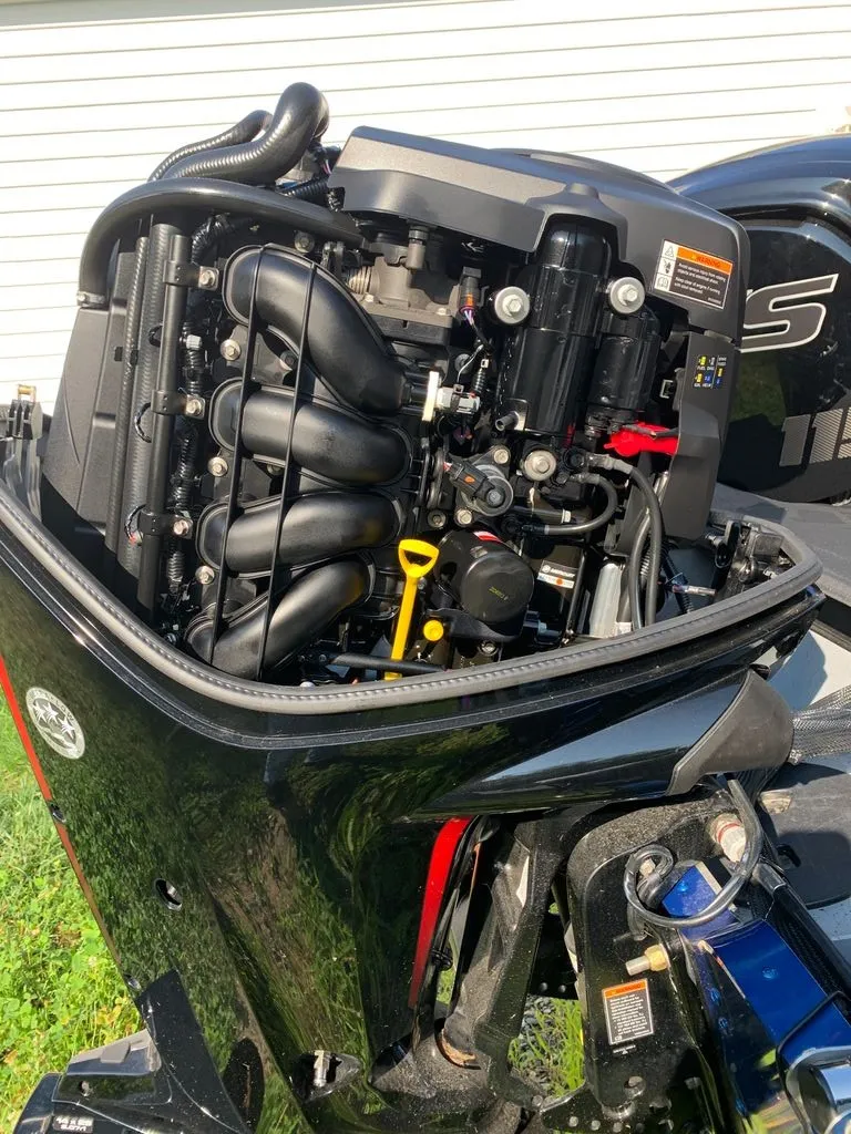 Slide: The Image of The engine of a 2024 Lund 1775 Adventure Sport boat is visible, showing hoses and components. - 12