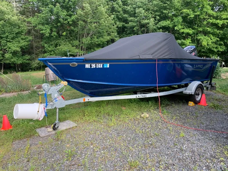 Slide: The Image of A blue 2024 Lund 1775 Adventure Sport on a trailer, covered, in a green setting. - 15