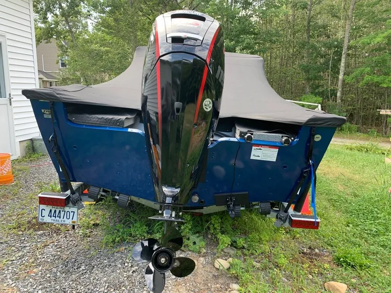 Slide: The Image of Rear view of a Lund 1775 Adventure Sport boat with a black outboard motor, parked on gravel. - 9