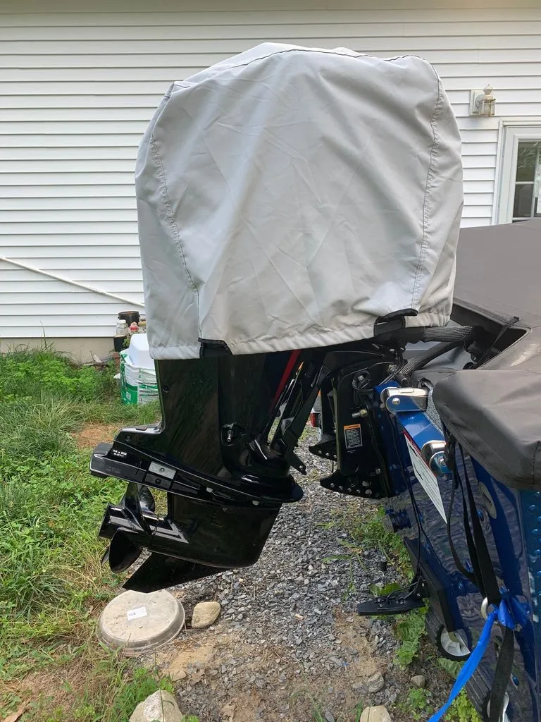 Slide: The Image of An outboard motor with a cover on a blue boat, parked on a gravel path. - 13