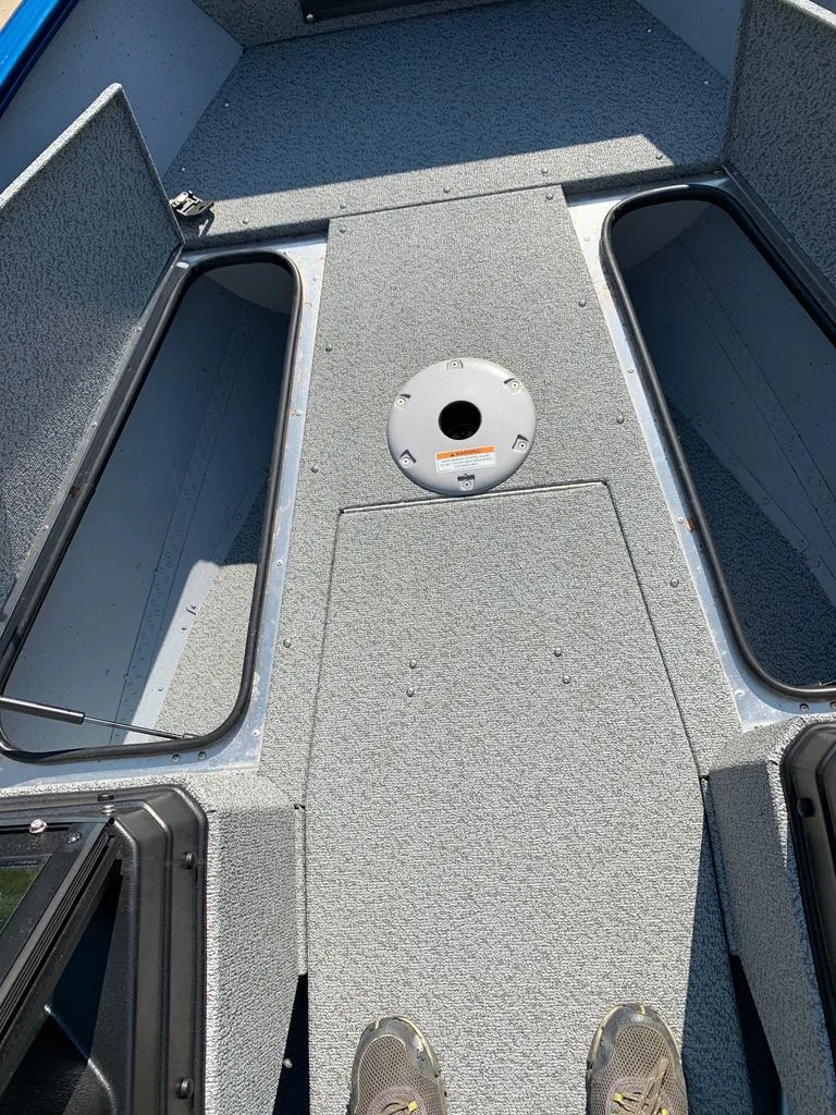 Slide: The Image of The image shows the interior of a 2024 Lund 1775 Adventure Sport boat with gray carpeting. - 3