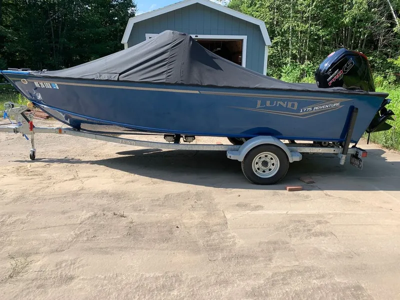 Slide: The Image of A blue 2024 Lund 1775 Adventure Sport on a trailer, with a cover and outboard motor. - 18