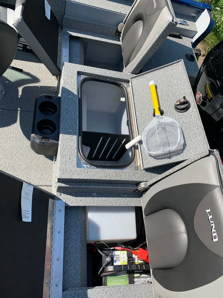 Slide: The Image of The image shows the interior of a 2024 Lund 1775 Adventure Sport boat with gray seats and a storage compartment. - 5