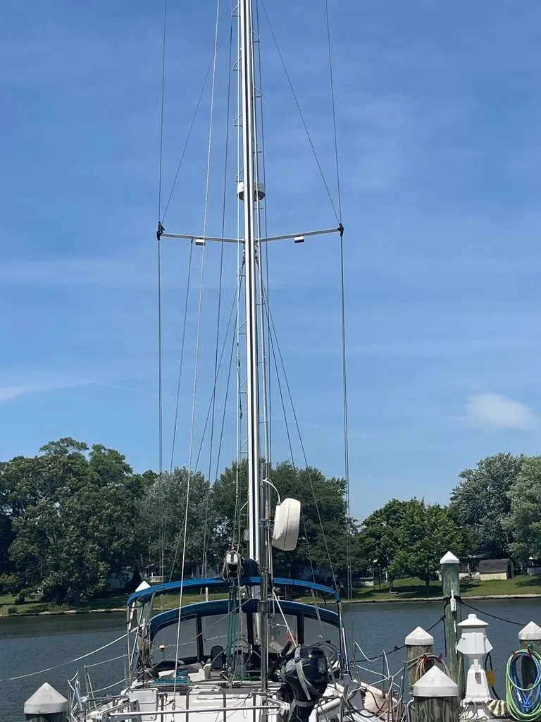 Slide: The Image of A 1985 Catalina Morgan 43 sailboat docked in a calm setting with trees in the background. - 1