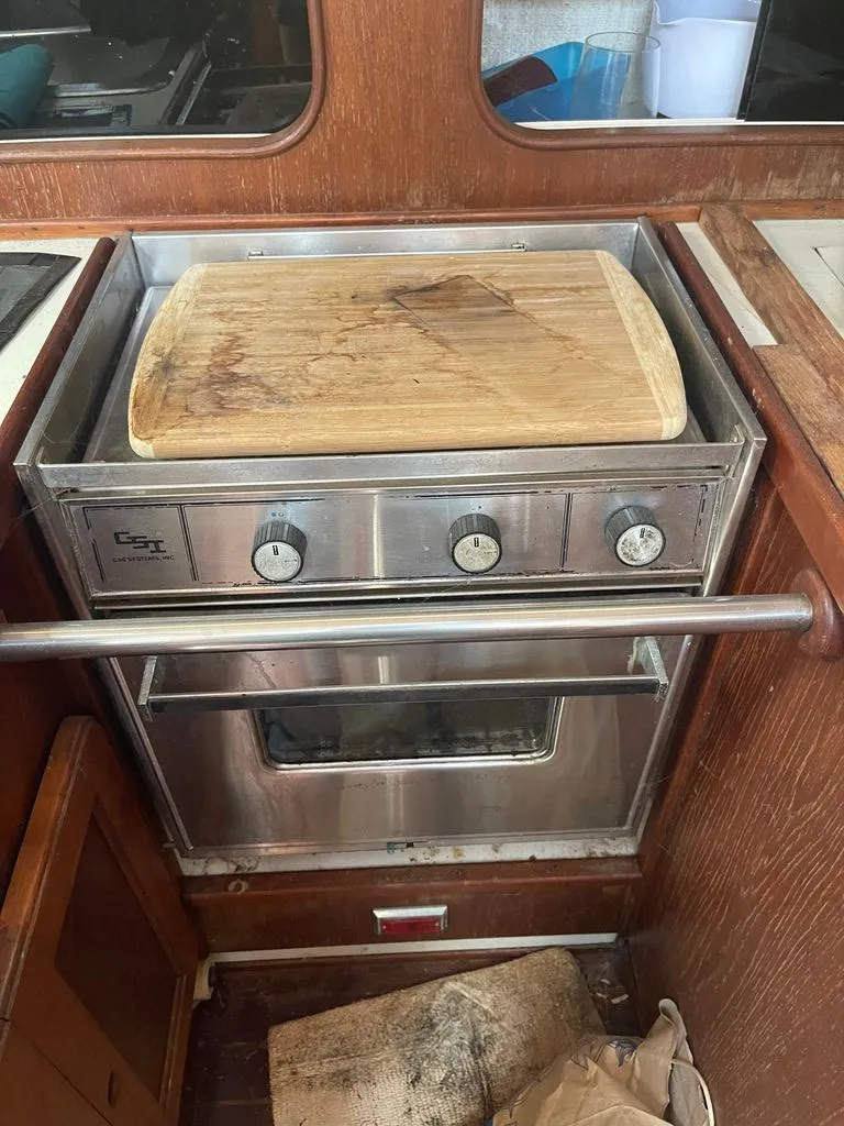Slide: The Image of A wooden cutting board sits on a stainless steel stove in a boat's galley. - 6